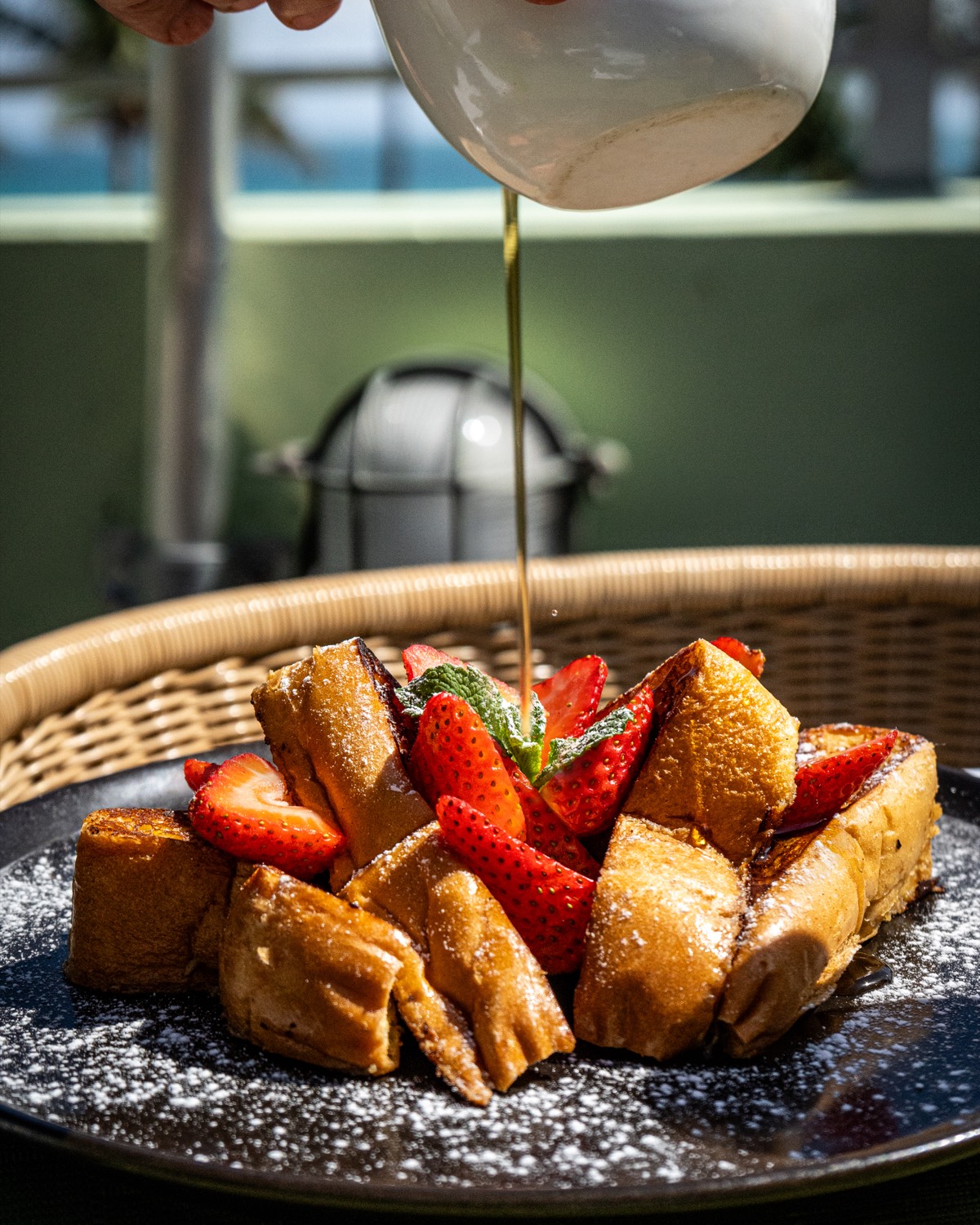 French toast with fresh strawberries, mint and maple syrup being poured at brunch on Ocean Drive, Miami Beach