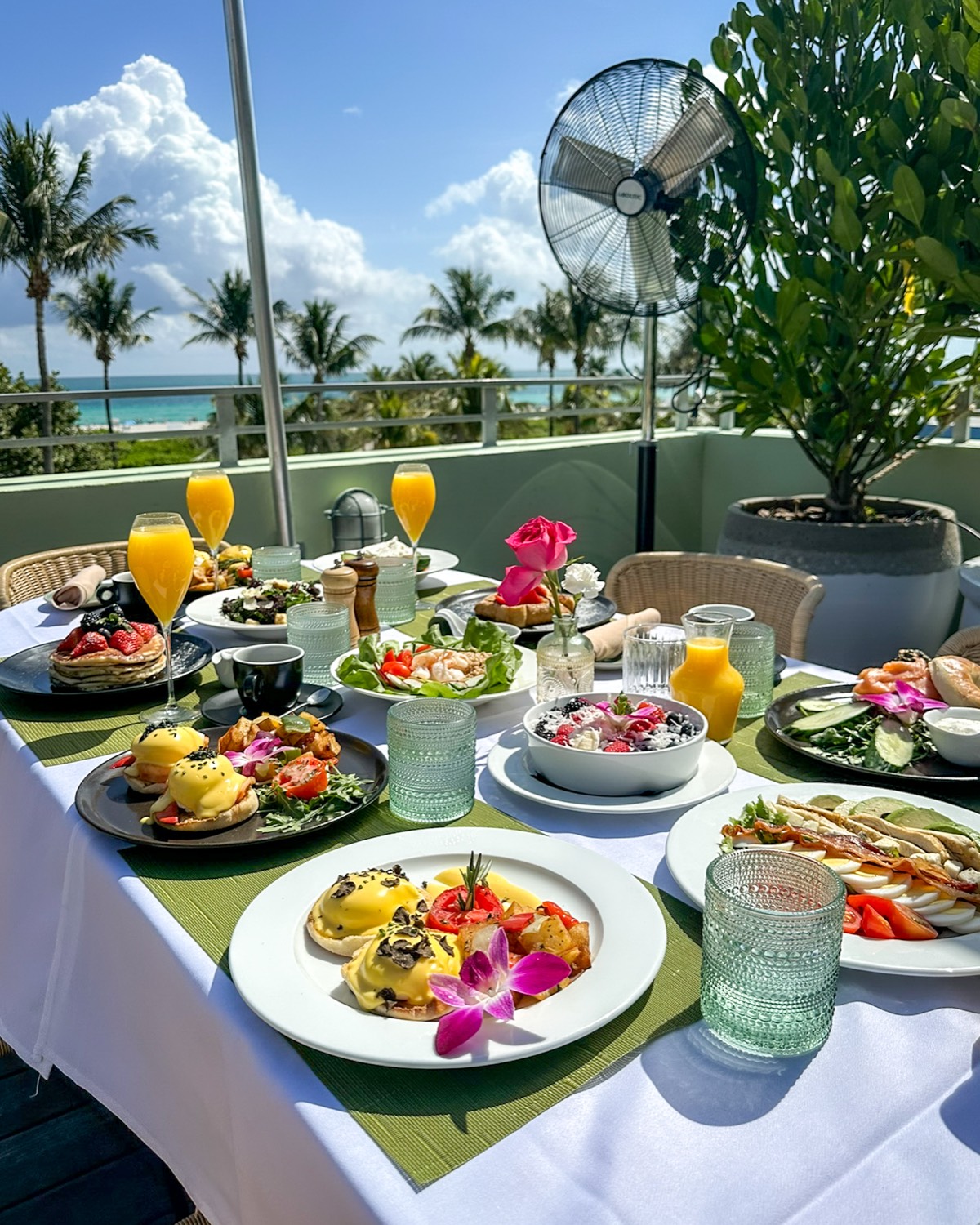 Sunday brunch spread on the Pelican Hotel rooftop with mimosas, eggs Benedict, pancakes and an ocean view in Miami Beach
